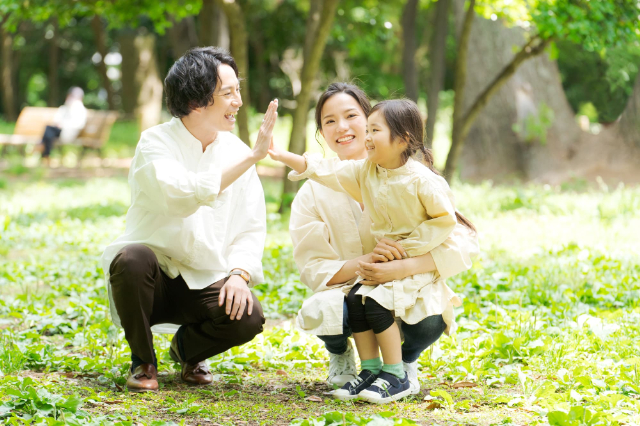 ハイタッチする父親と女の子と二人を見つめる母親